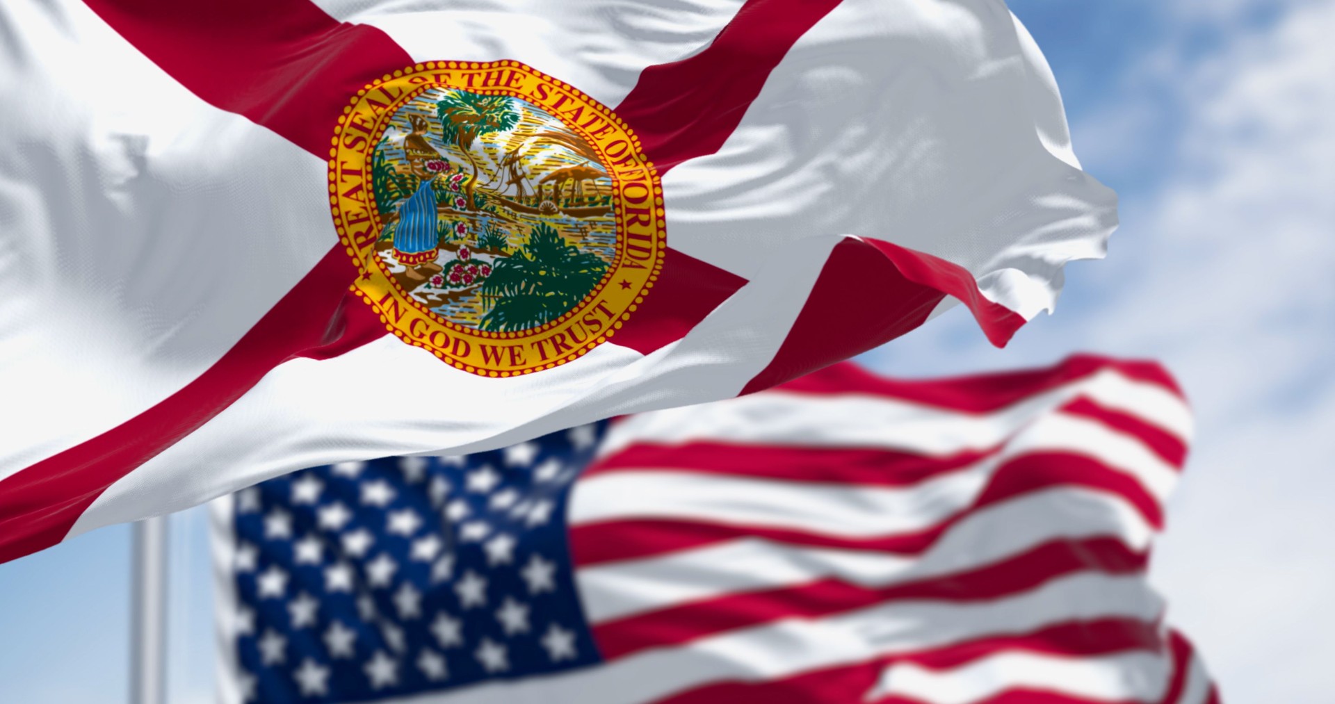 Flags of Florida and United States waving in the wind on a clear day